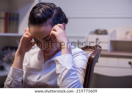 young tired woman with closed eyes holding at her head and thinking hard about big problems in her company. Her