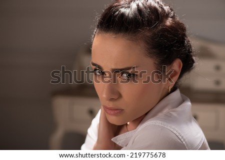 young woman wearing white blouse looking at us with piercing glance. Her office on background
