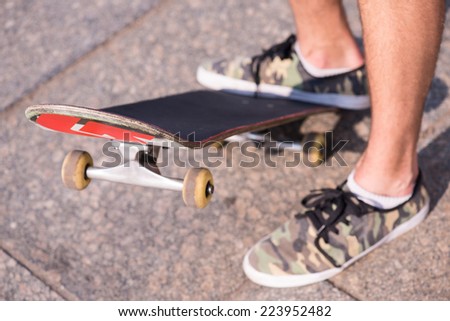 Selective focus on the skateboard under the man foot wearing sneakers