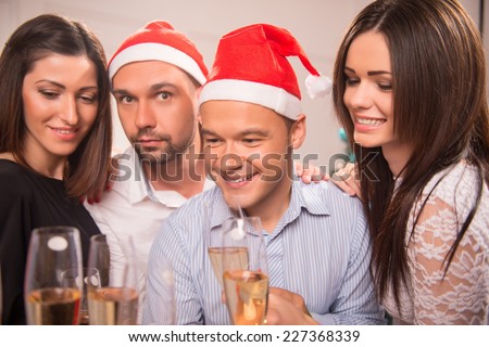 Half-length portrait of the company of happy young smiling friends standing together drinking the champagne greeting each other with the New Year
