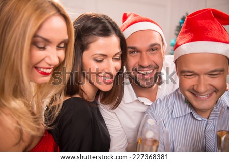 Half-length portrait of the company of happy young smiling friends standing together drinking the champagne greeting each other with the New Year
