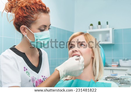 Half-length portrait of young dentist wearing medical mask treated teeth of her new young patient sitting on the dentist chair