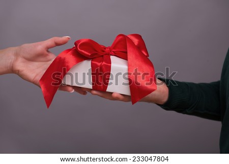 A great present cording with the red band in the hands of two people in love. Isolated on grey background