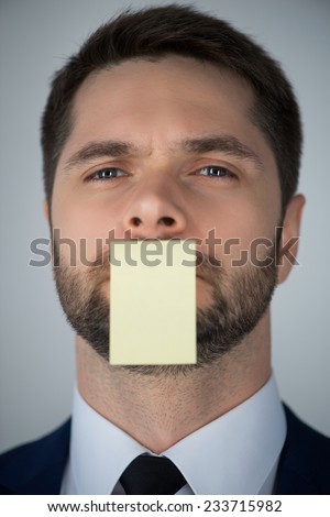 Half-length portrait of handsome young man wearing white shirt tie and blue suit having on his mouth a sticker for the copy place. Isolated on white background