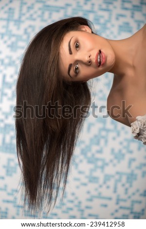 Selective focus on the beautiful sexy dark-haired woman bending her head showing us the length of her hair