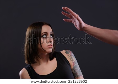 Victim of domestic violence. Young terrified teenage girl looking with fear at the male torturers hand while standing against dark background