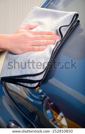 Checking his ideal work. Closeup of car mechanic hand polishing the luxury car with wiper in car repair shop