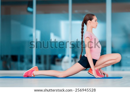 Practicing yoga. Beautiful teenage girl in sports clothing training yoga position on the mat in health club