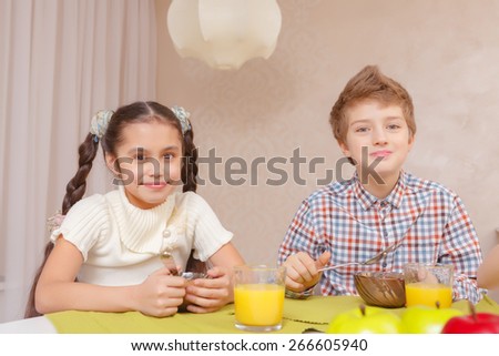 Best time for lunch. A schoolboy and a schoolgirl smiling at a camera while having lunch at home