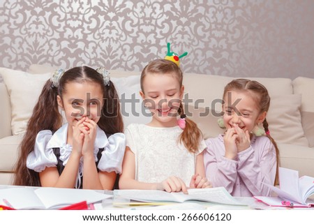 Tutoring each other. Three pretty schoolgirls writing home tasks in exercise books sitting at home