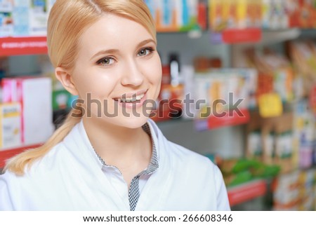 Healthcare in action. Close-up of an attractive young pharmacy chemist and blurred rows of medicine on the background