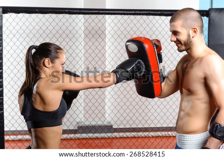 Sparring fight. Female mixed martial art fighter training with a couch in fighting cage