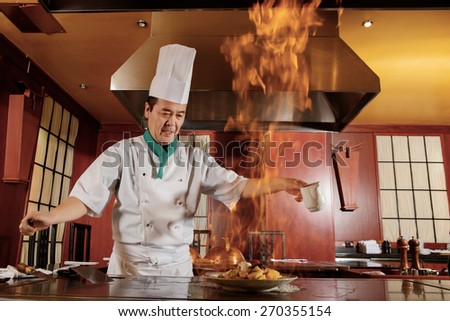 Kitchen hell. Japanese cook frying a vegetarian meal in burning flame of spirit on restaurant kitchen