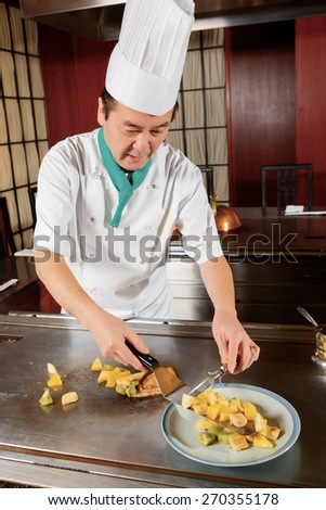 Original taste. Chef-cook puts cooked fruits and pancake on a plate at oriental cuisine restaurant