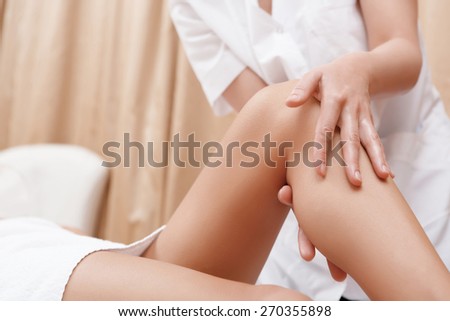Slim legs. Close-up of a masseuse massaging legs of a young woman in spa center