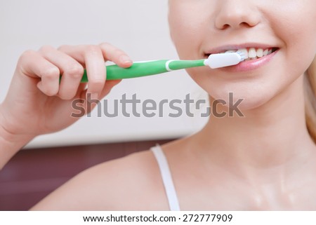 Substantial cleaning. Pretty young woman standing in front of mirror and cleaning her teeth
