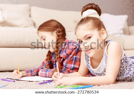 Creativ work. Two involved in creative work  little girls lying on carpet and drawing with help of colorful crayons and markers
