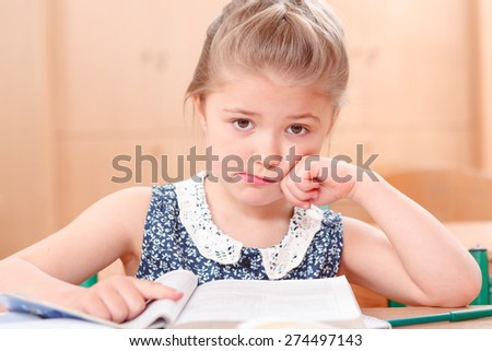 Reading is sad .Little pretty girl is sad while reading book during classes.
