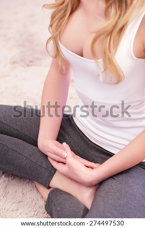 Closed pose. Woman sitting on carpet in lotus pose and with hands across.