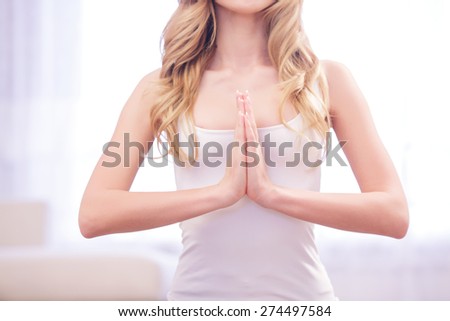 Inner power. Young blond-haired woman putting her palms together on her chest area on white background.