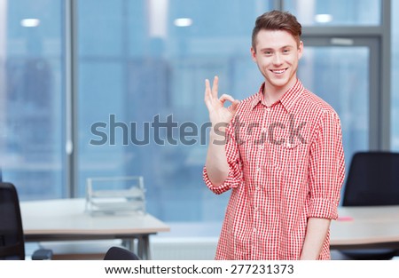 It is ok. Portrait of young office worker standing in office and pointing ok.