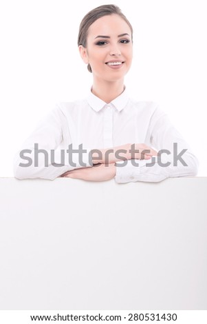 Portrait of a beautiful young lady wearing glasses and formal white shirt smiling standing behind a white copyspace holding her arms crossed, isolated on white background
