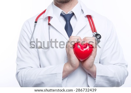 Feal the beat. Young cardiologist holding the heart in his hands with care while standing on white background.