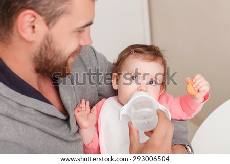 Time to eat. Selective focus of little child looking at father feeding it with baby bottle .