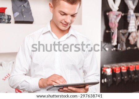 Online shopping. Portrait of young man holding tablet in boutique and using it.