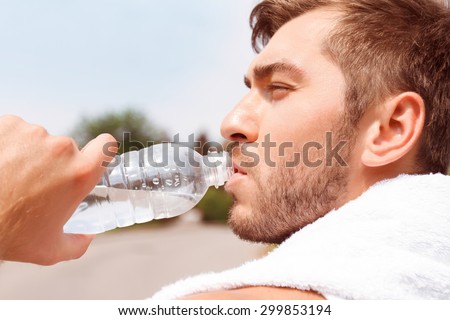 Lets restore energy. Close up of nice guy drinking water while having rest after running.