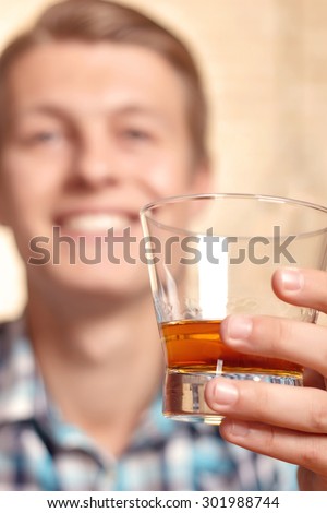 Best quality. Close up portrait of young man holding cup with expensive strong alcohol.