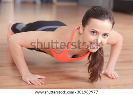 Sincere smile. Close up portrait of young pretty woman doing push ups in gym