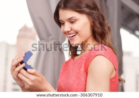 What a beauty. Portrait of young attractive happy woman holding ring case in restaurant.