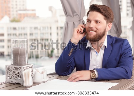 Sweet conversation. Portrait of young attractive man sitting in restaurant and talking per mobile phone.