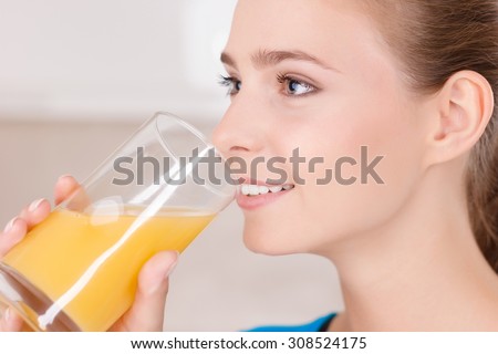Best way to wake up. Nice vivacious young girl holding glass and drinking juice while having breakfast in the kitchen