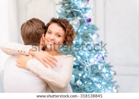 Love of my life. Pleasant jubilant positive young couple embracing and expressing joy while standing near Christmas tree