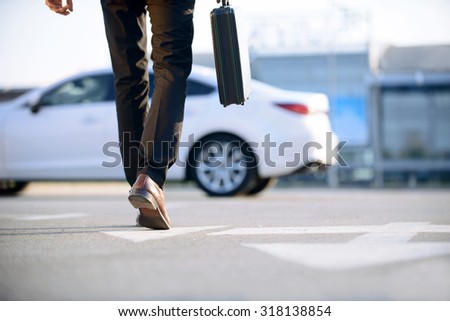 In pace of time. Modern young businessman holding case and going to his car while evincing confidence.
