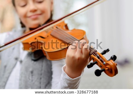 A way to success. Close up of pleasant vivacious pretty girl holding fiddle bow and learning to play the violin