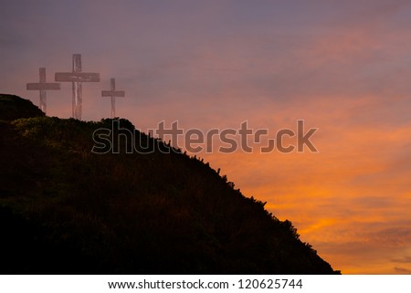 Three crosses on a hill at sunrise