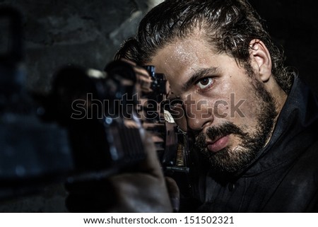 Young soldier holding gun, dressed in black, underground. Special Forces