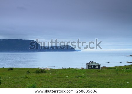 Blue wooden cabin on the shore in Nordic landscape