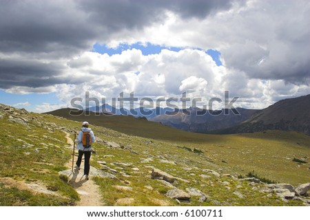 Hiker among yellow and sunny green colors of the mountains prairies forests in Cordeliers during late summer early fall