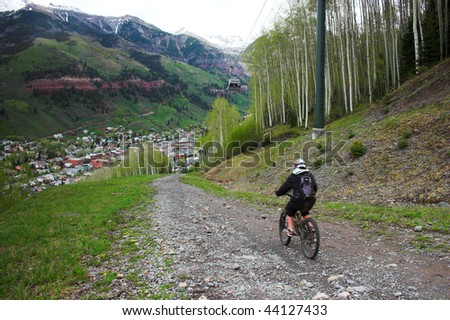 Person doing mountain biking through forest to town in Colorado