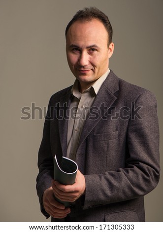 businessman in a suit holding his hand and the magazine looks at the camera, age thirty-five, thirty-seven years