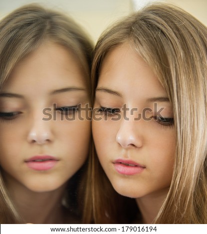 Portrait of a beautiful young girl at the mirror. Cute girl standing pressed against his clinging to the mirror image.