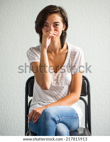 Chinese woman sitting on a chair on a background of bright wall
