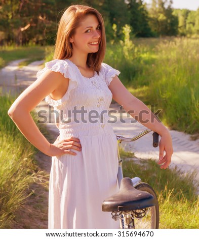 woman walking with a bicycle bright sunny day near the forest