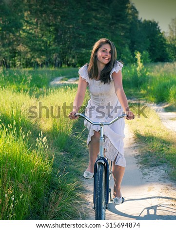 Girl rides a bicycle summer day in the countryside