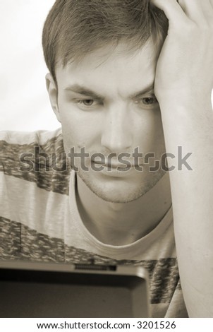 young man -  student with concentration works on  computer, close up