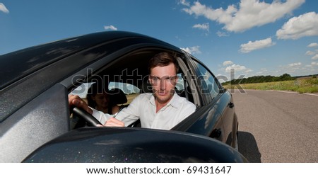 young nice businessman at the wheel in the car on the journey, a sunny day
